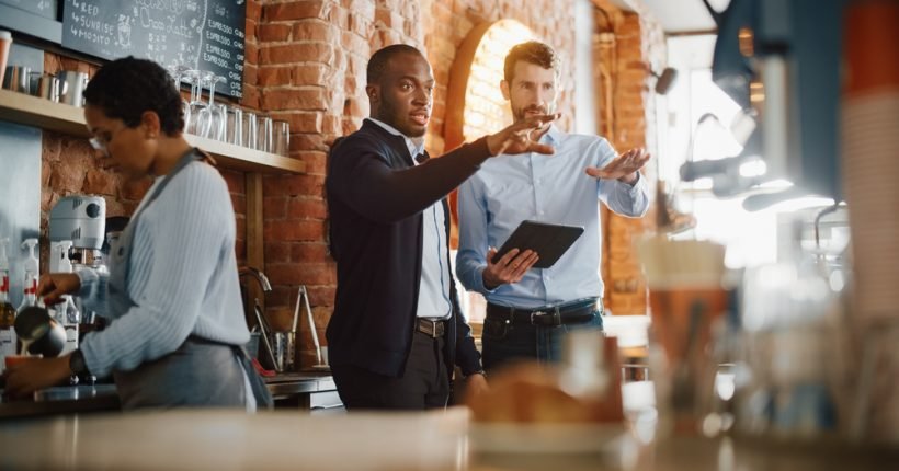 Multicultural,Coffee,Shop,Owners,Meeting,Behind,The,Counter,And,Working